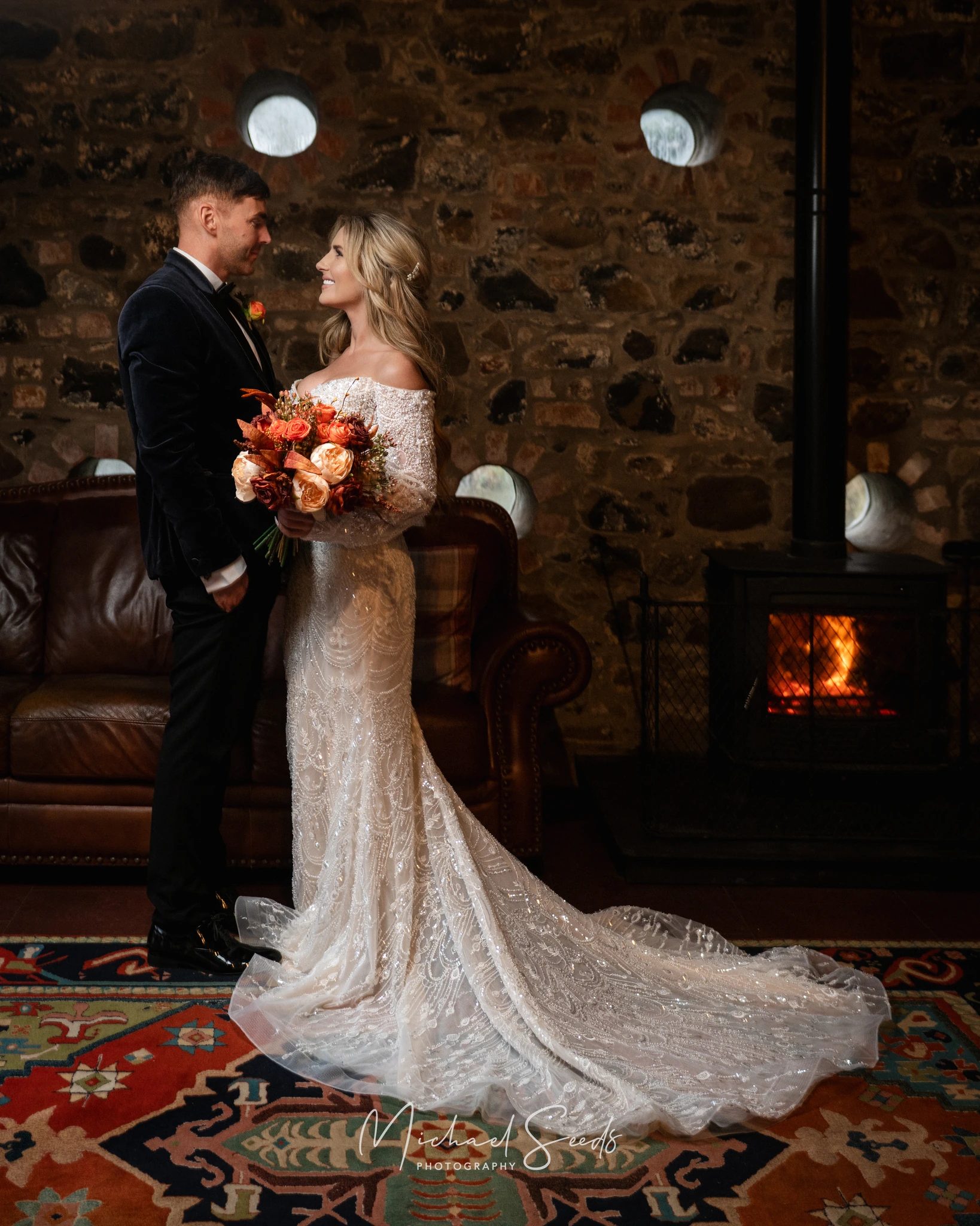 a bride and groom standing in front of a fireplace