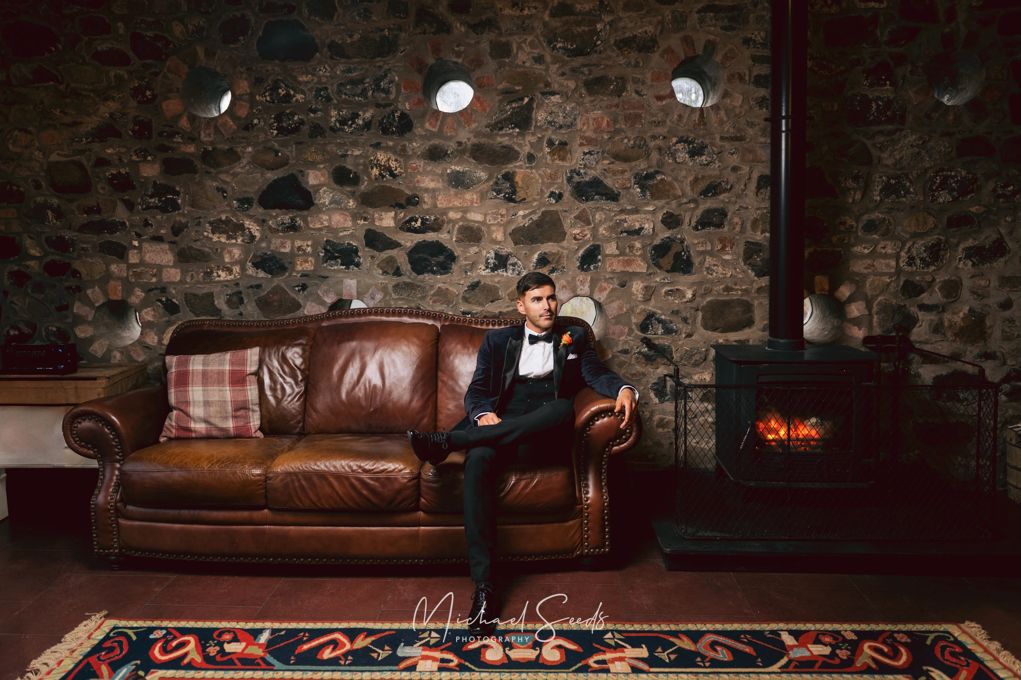 a man sitting on a sofa in front of a fireplace