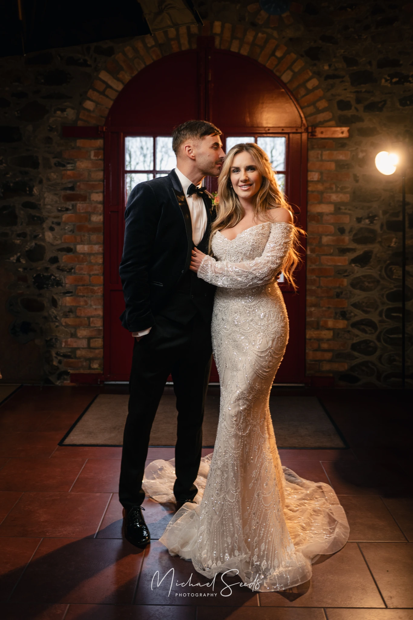 a bride and groom pose in front of a fireplace