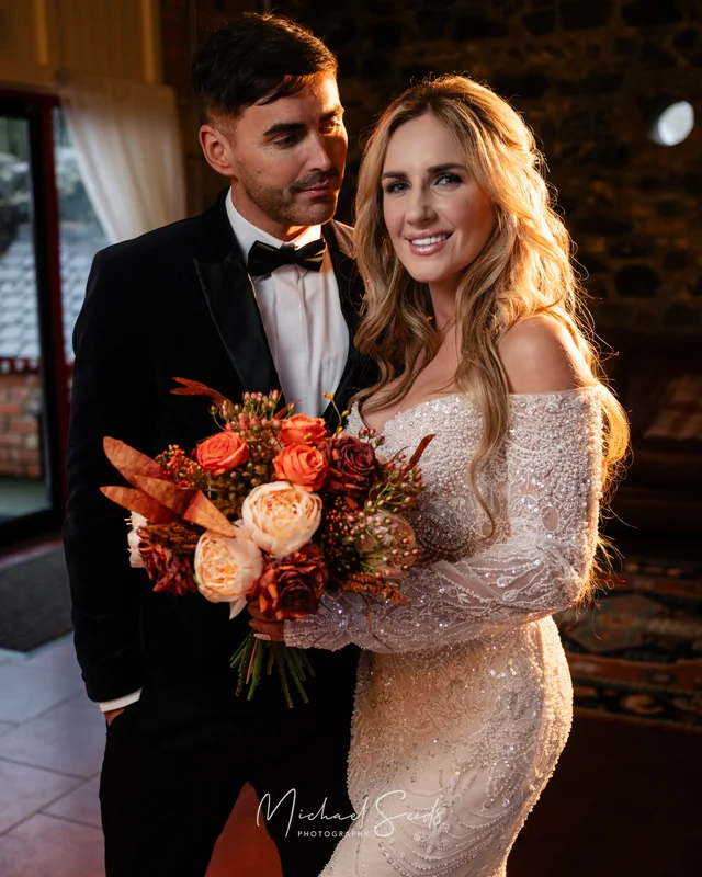 a bride and groom standing in front of a fireplace
