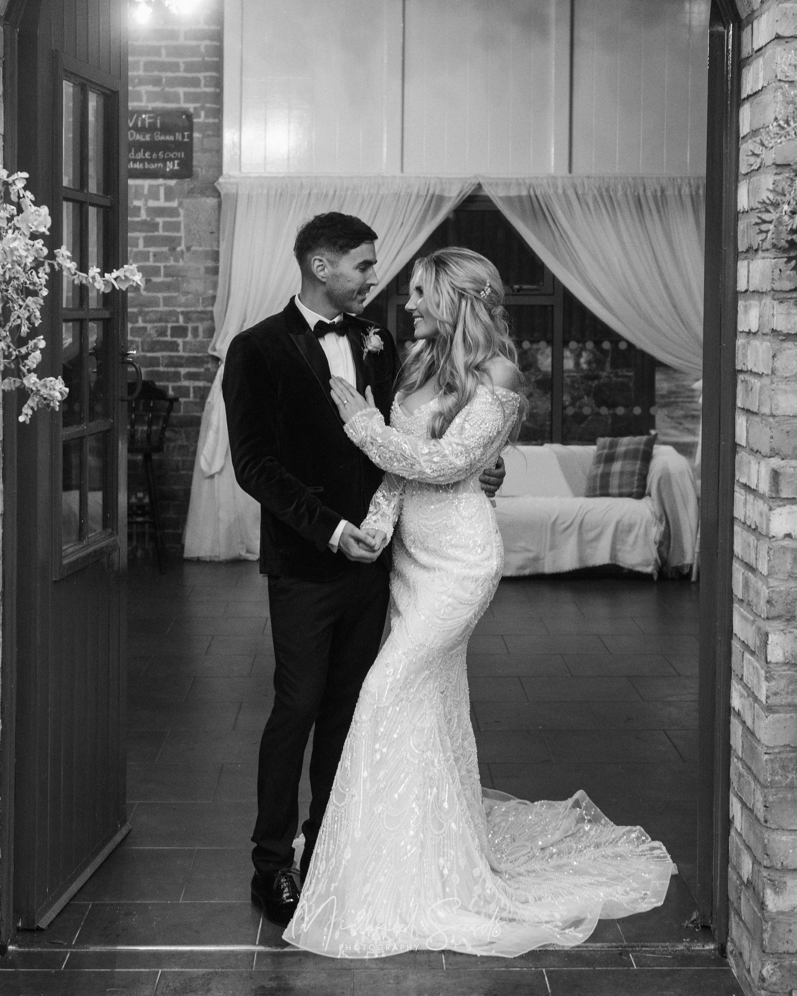 a bride and groom embrace in front of a doorway at their wedding reception