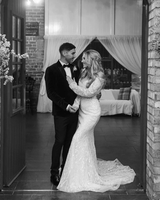 a bride and groom embrace in front of a doorway at their wedding reception