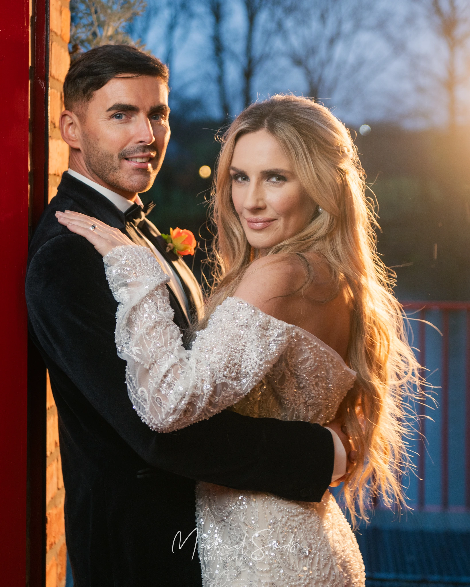 a bride and groom posing in front of a red brick wall