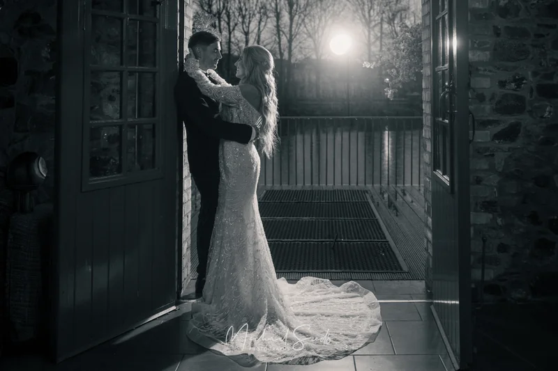 a bride and groom kiss in front of a barn door